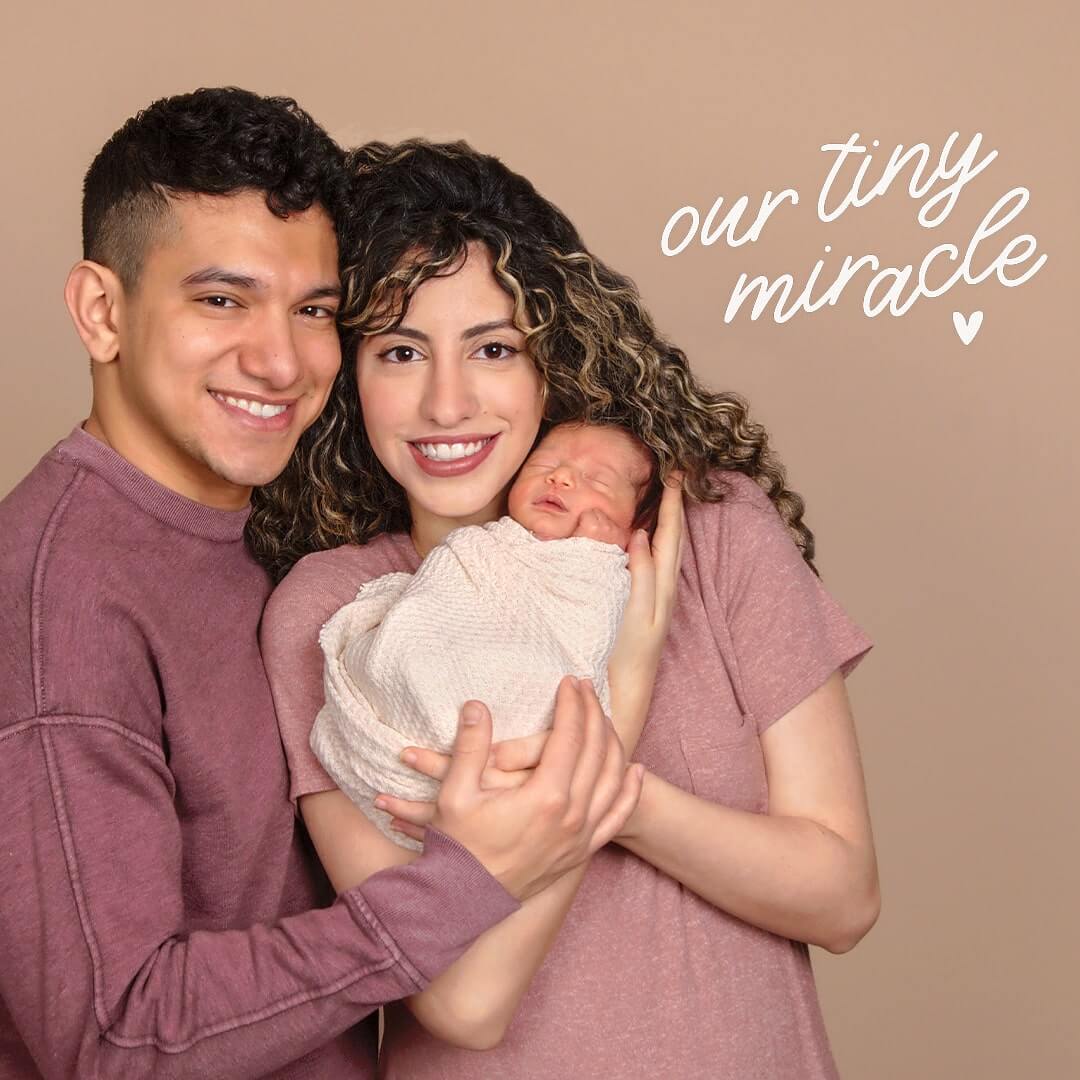 Couple posing with their newborn on a latte background