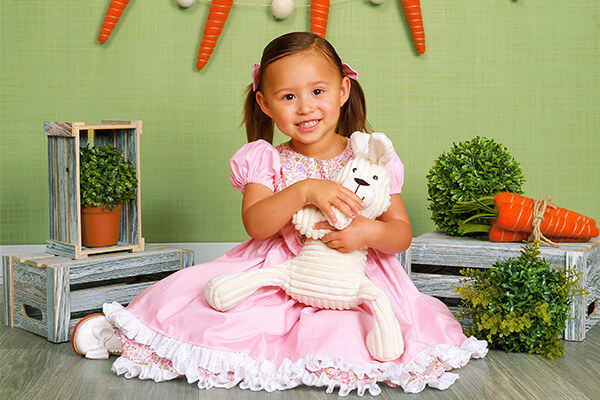 Girl in a pink dress smiling for Easter photos at JCPenney Portraits.