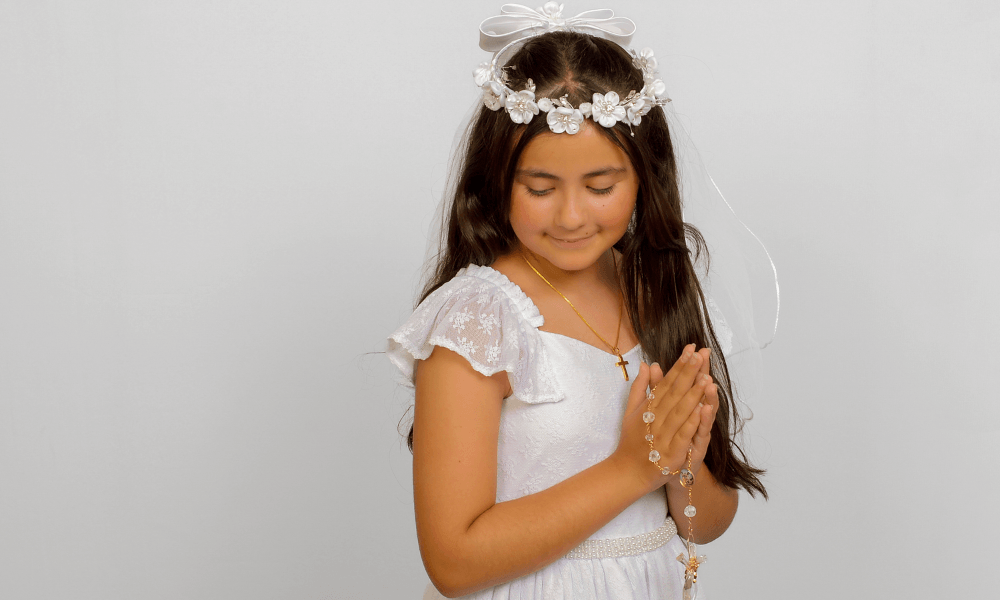 Girl in a flower veil and white dress photographed for First Communion pictures.
