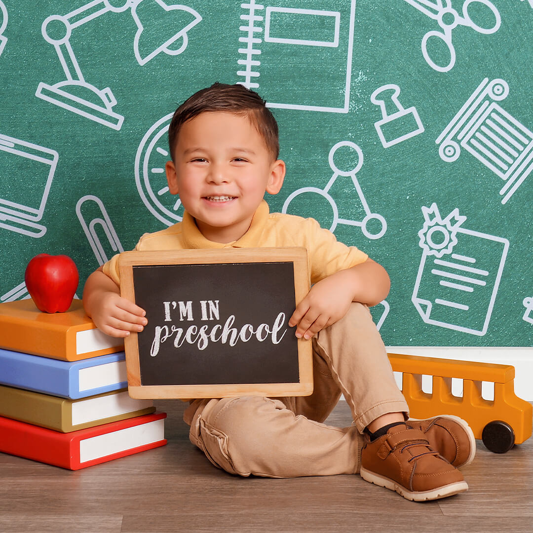 Boy holding a preschool sign for a back to school photos.