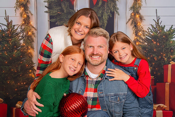 Family of four smiling for professional Christmas pictures at JCPenney Portraits.