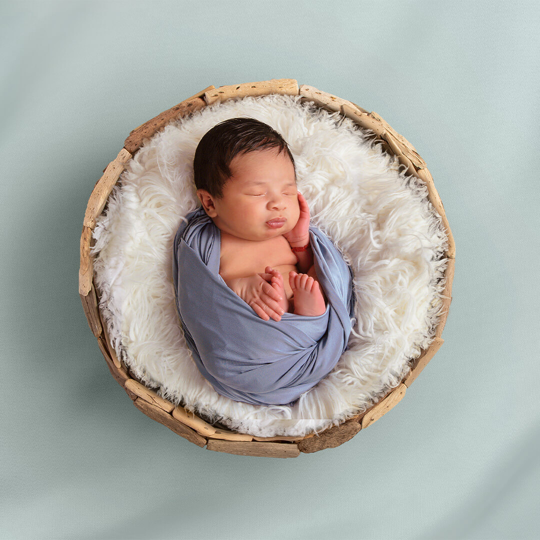 Newborn photo enhancement featuring a blue floor, basket, and white fur