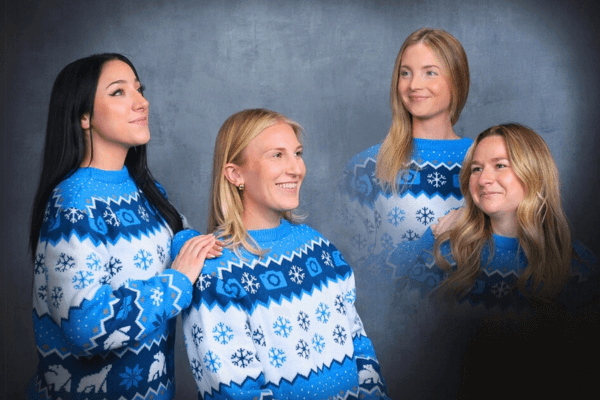 Four women in holiday sweaters posing for awkward holiday photos