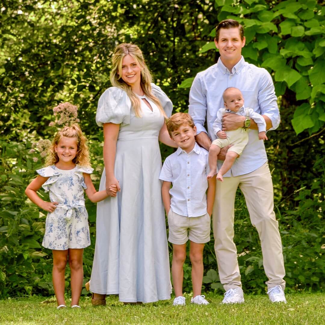 Family of 5 dressed in spring attire posing for outdoor photos.