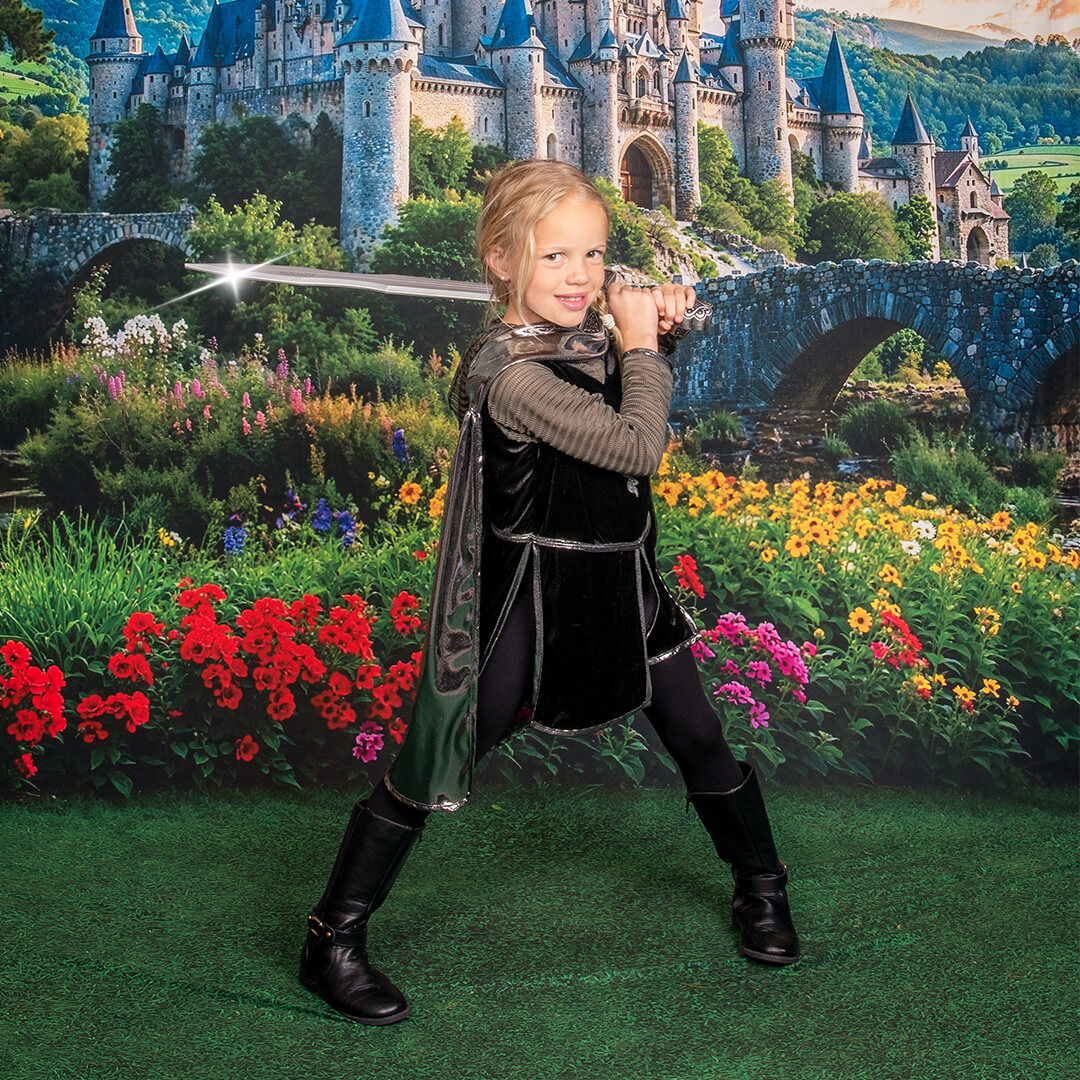 Boy dressed in a knights costume holding a sword.