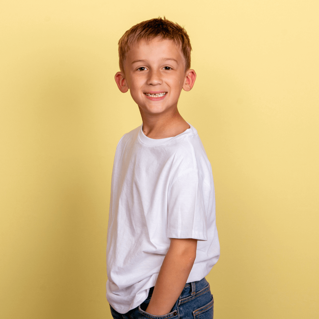 Boy in a white tshirt posing for pictures on a yellow background.