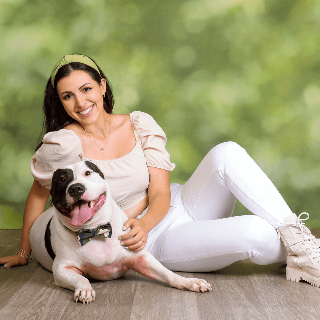 Woman posing for pictures with her dog on an outdoor bokeh background.