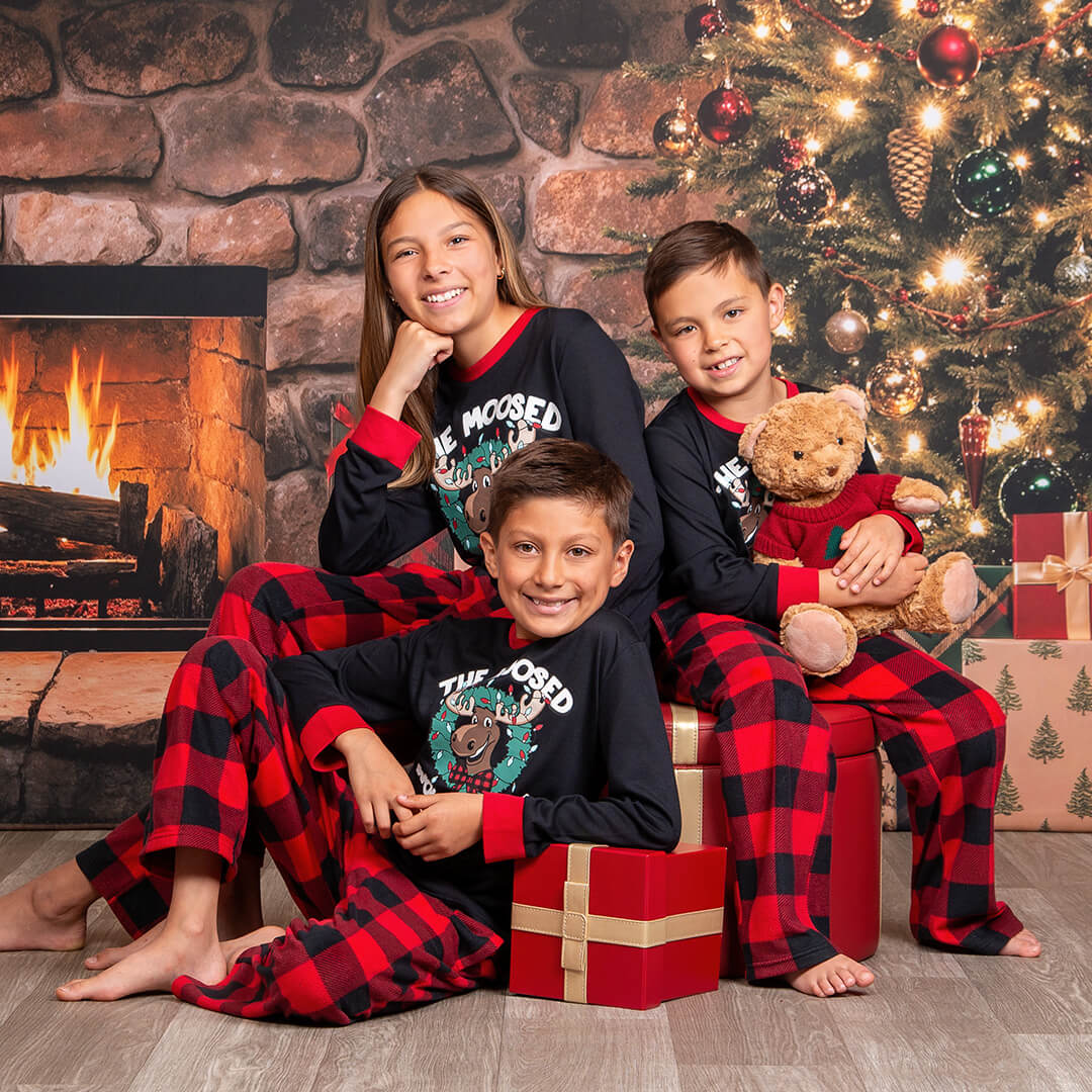 Siblings in pajamas posing for holiday photos.