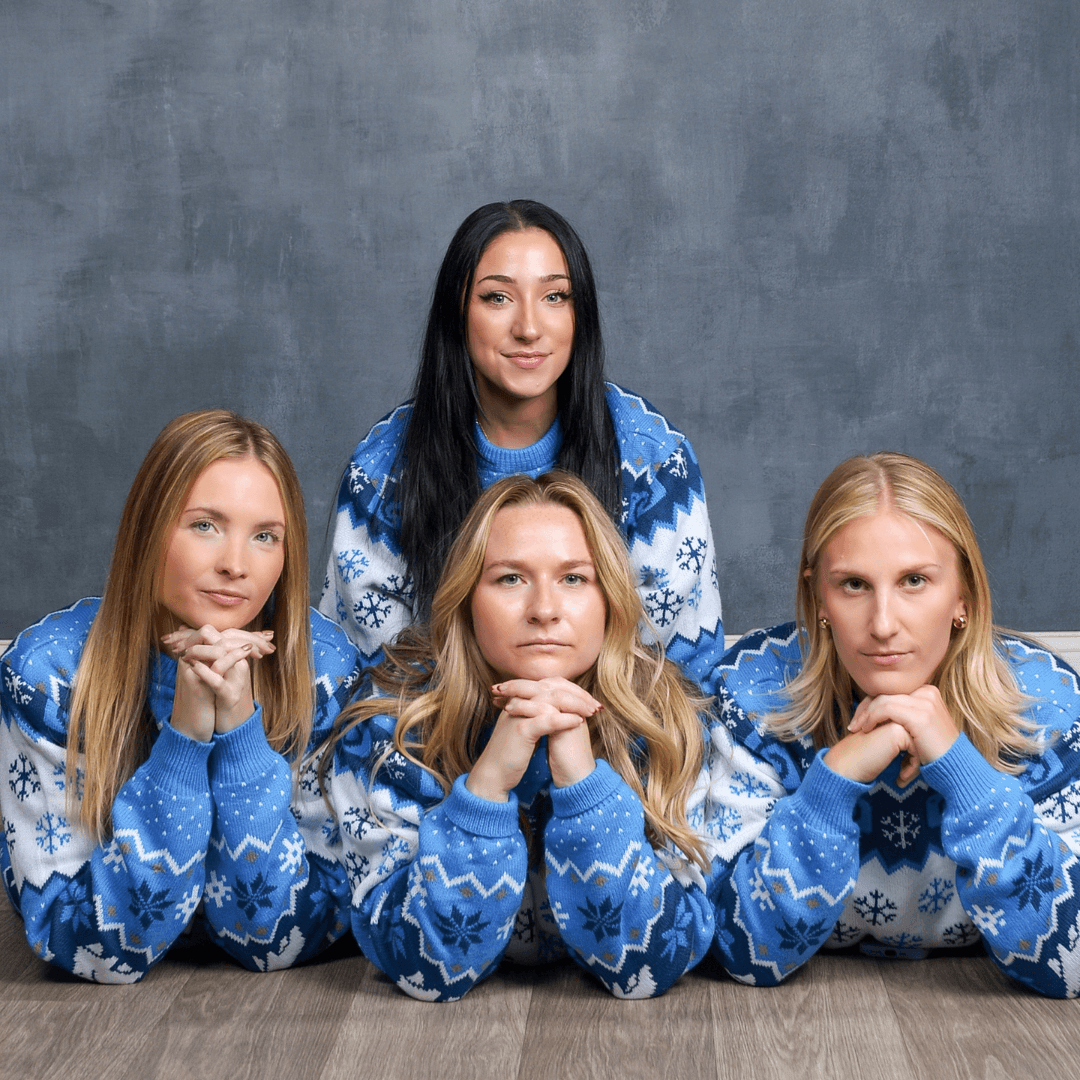 Four women in holiday sweaters posing for awkward holiday photos