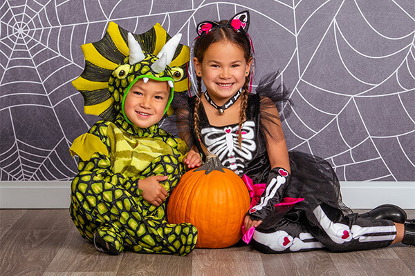 Siblings in Halloween costumes posing for Halloween sibling pictures.