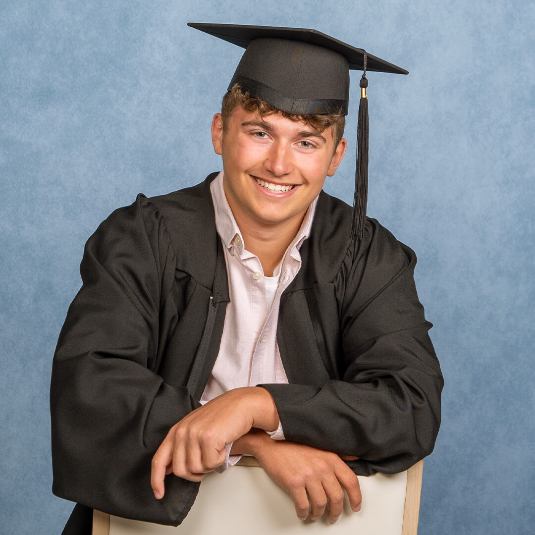 Grad in a black cap and gown for professional graduation photos.