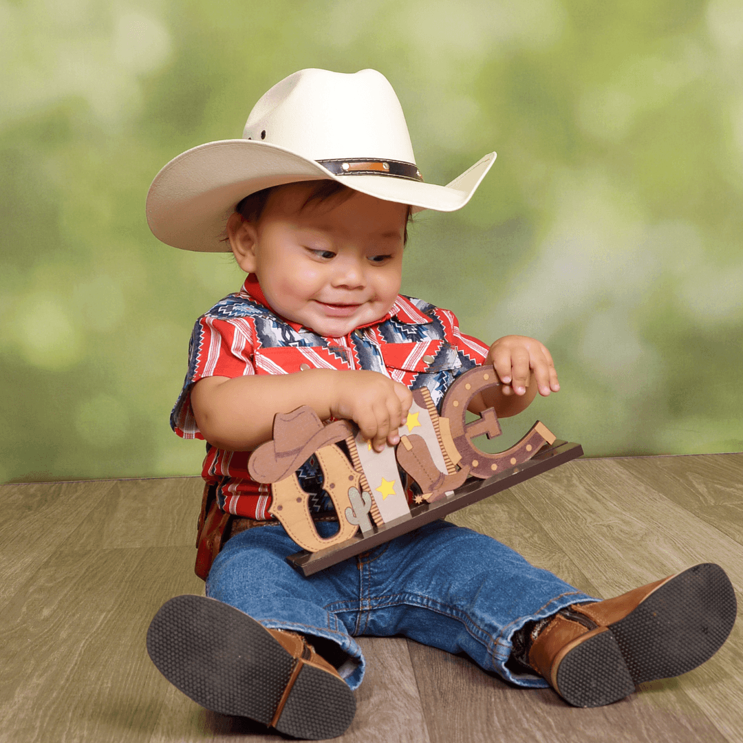Boy in a cowboy outfit for one year birthday pictures.