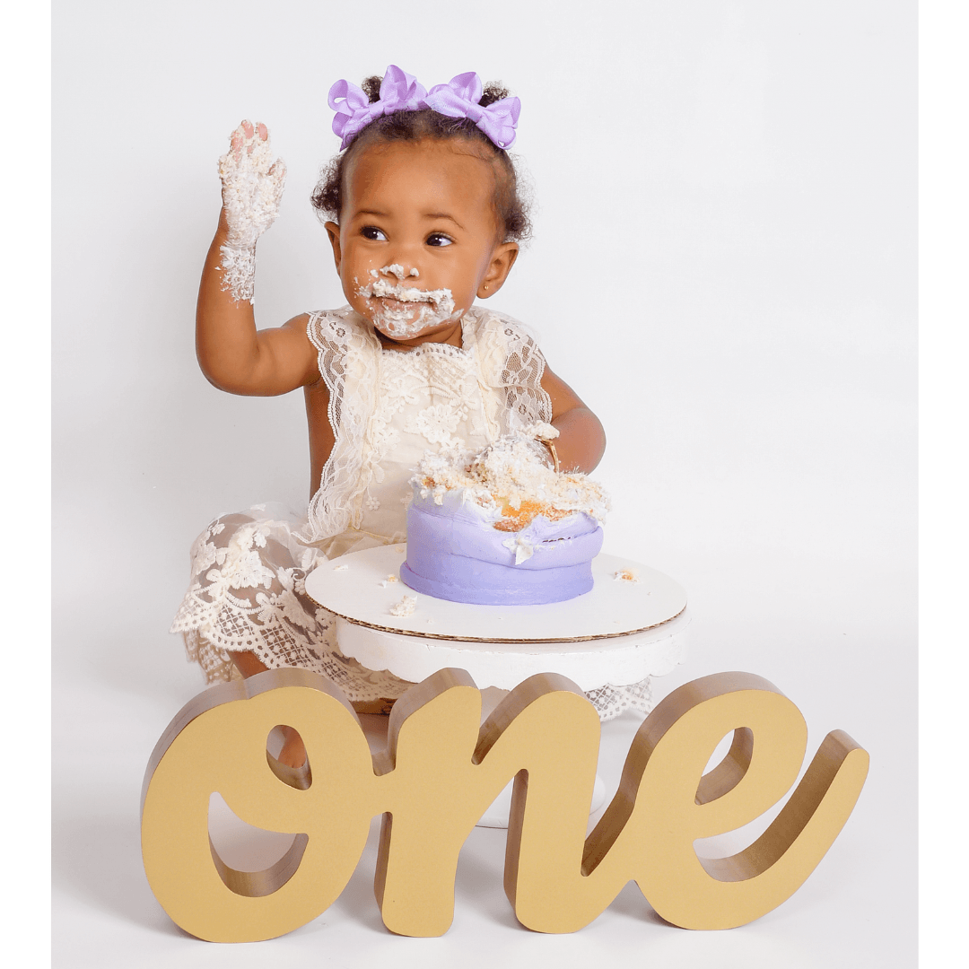 Baby eating birthday cake for a one year birthday photoshoot.