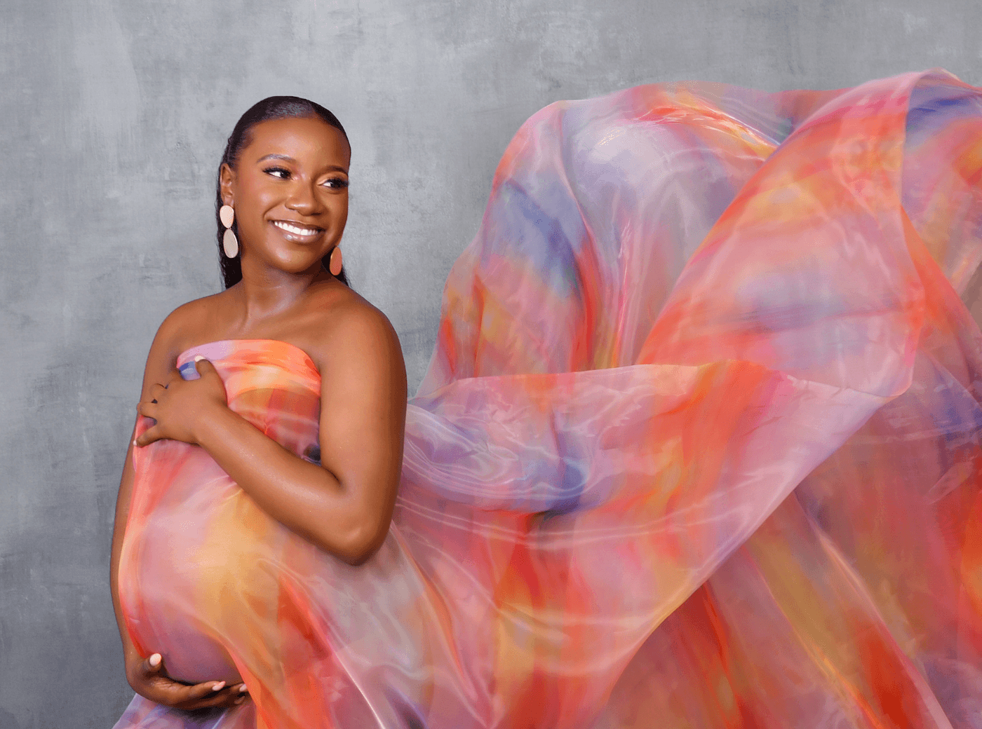 Woman in a billowing multi-colored dress for maternity photos at JCPenney Portraits.