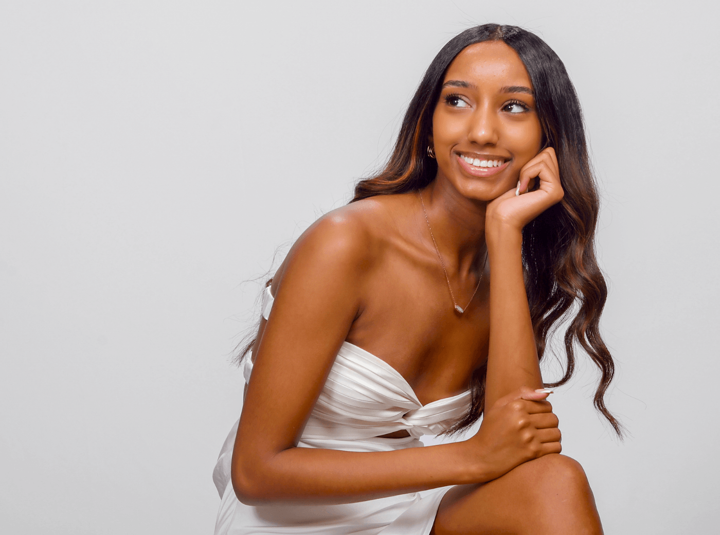 Senior female in a white dress and white background for professional senior pictures.
