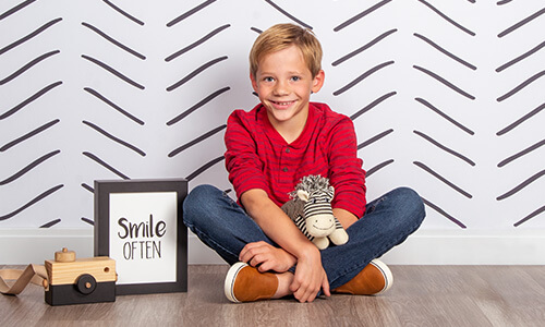 Boy smiling for professional children pictures on Herringbone background at JCPenney Portraits.