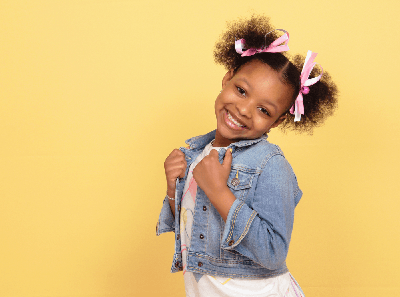Girl in a denim jacket smiling for professional child photos at JCPenney Portraits.