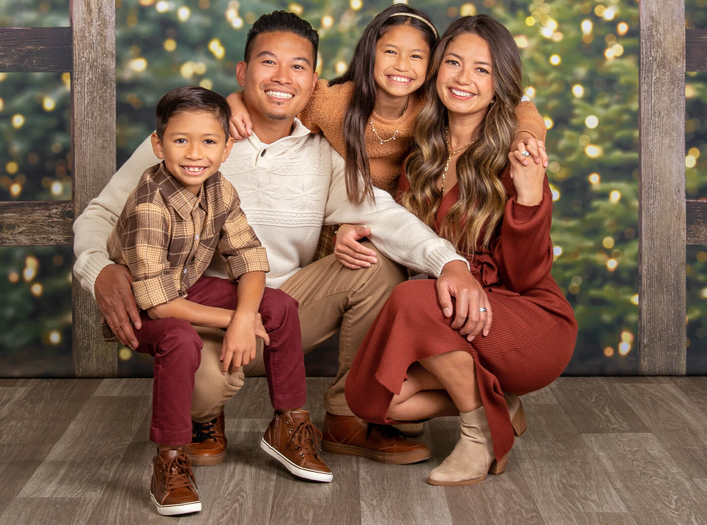 Family of 4 smiling for professional Christmas family photos at JCPenney Portraits.