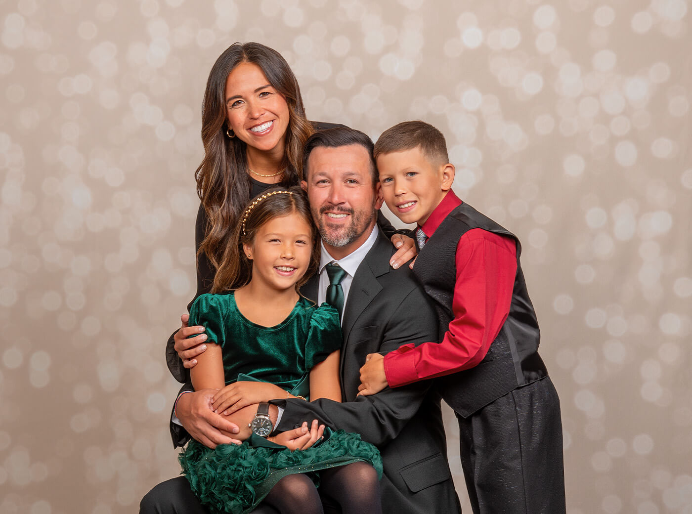 Family of 4 dressed up for a Christmas photoshoot on the Shimmer background at JCPenney Portraits.