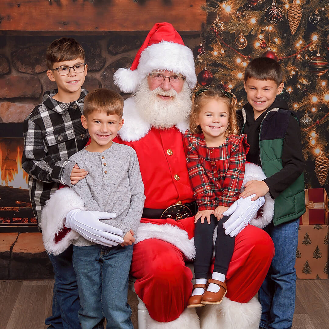 Group of children smiling for pictures with Santa at JCPenney Portraits.