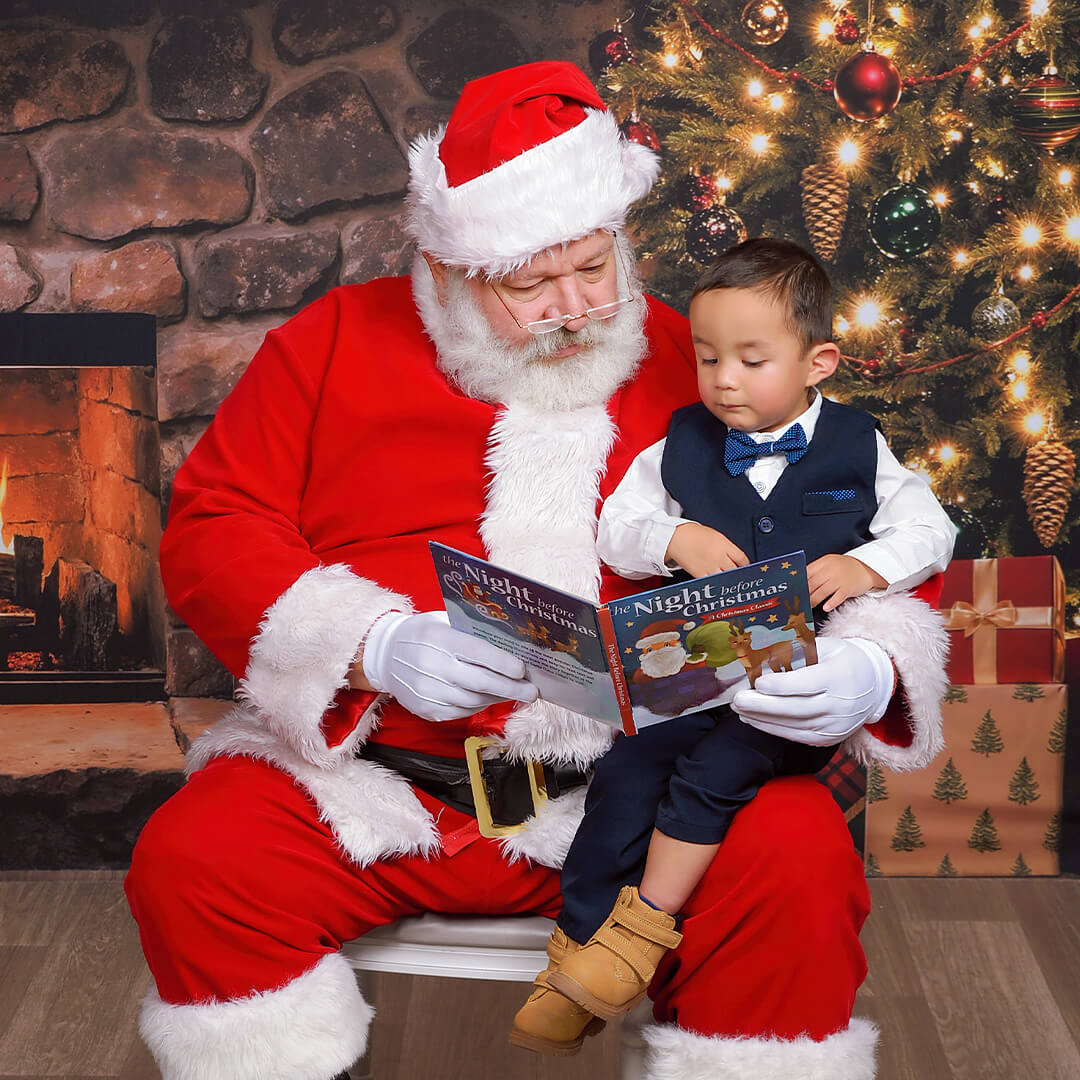 Boy reading a book with Santa for Santa pictures at JCPenney Portraits.